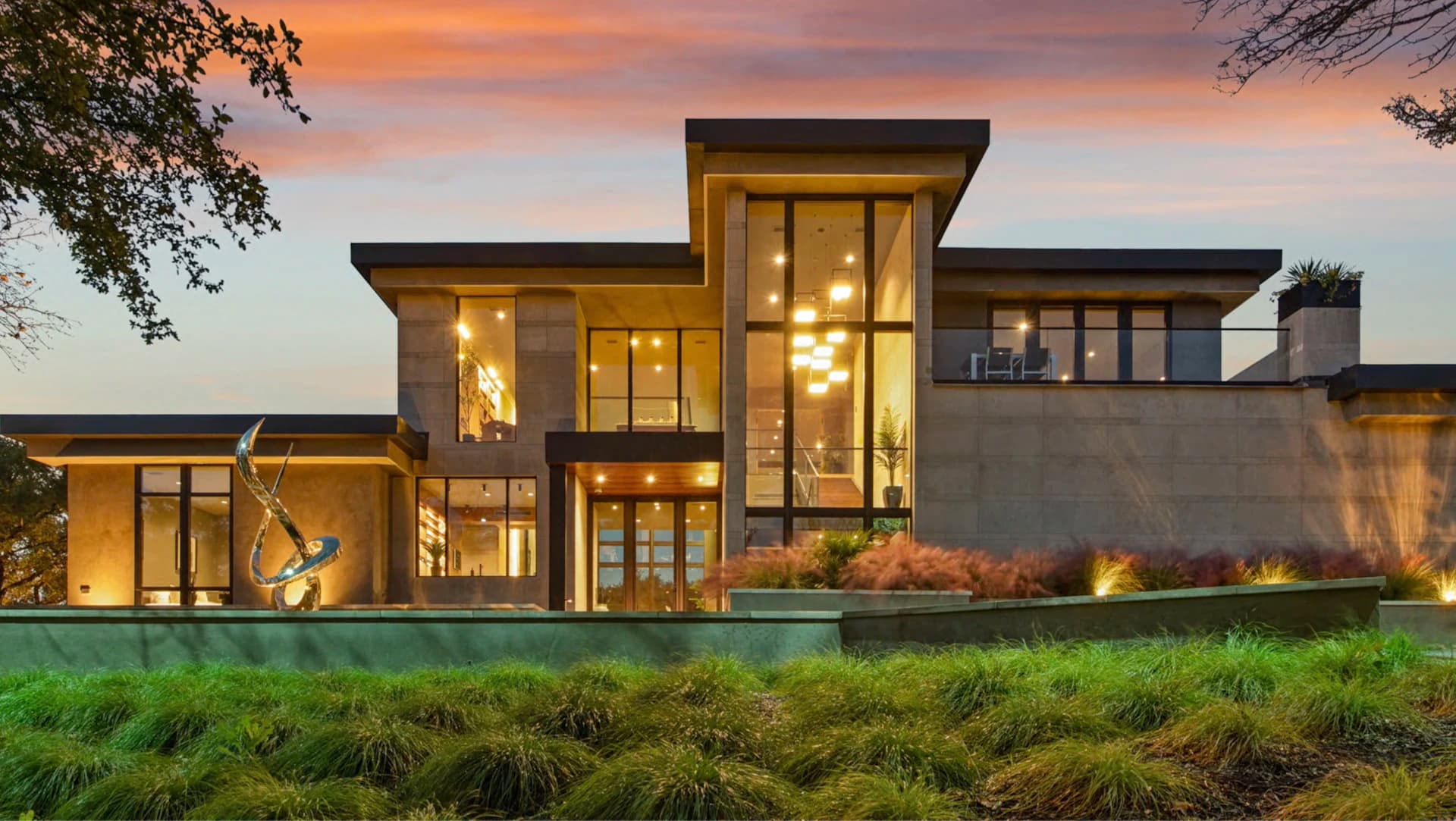 Architecturally lit luxury home exterior at dusk with warm amber landscape lighting